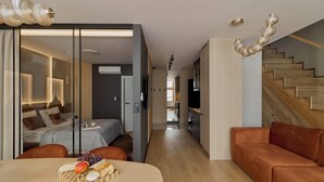 Ein modernes Interieur mit Essbereich, Sofa, Treppe und einem Schlafzimmer mit Bett und Nachttisch.