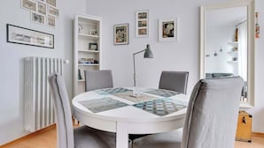 Una mesa redonda para comer con sillas, un radiador y estantes con marcos y fotografías.