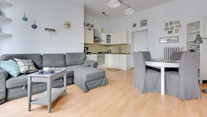 Una sala de estar moderna con un sofá gris, una mesita y un comedor con sillas.