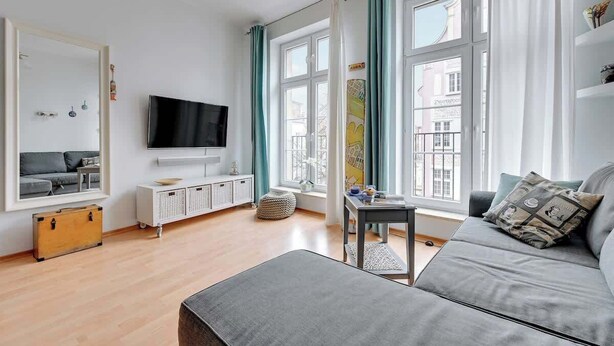 Una sala de estar moderna con un sofá, un televisor, una mesita y una ventana con cortinas.