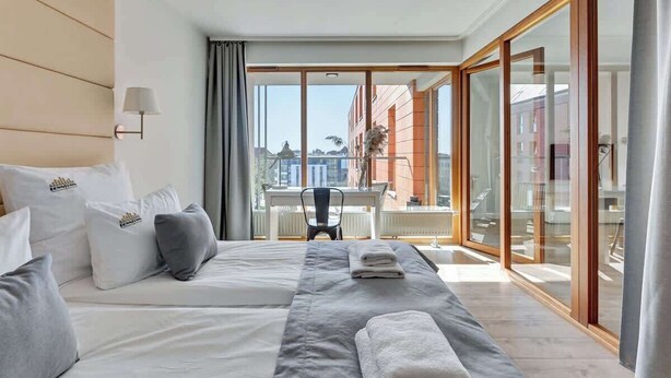 Habitación de hotel con cama, escritorio y vista a edificios.