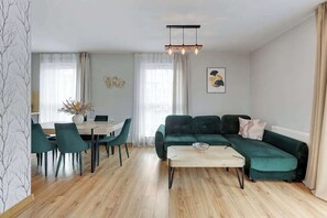 A modern living room with a sectional sofa, dining table, chairs, and a coffee table. - Angielska Grobla 199 | Near Old Town & Marina (Gdańsk)