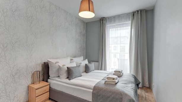 Una camera da letto con un letto, comodini, una finestra con tende e una lampada a sospensione.