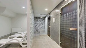 Un cuarto de spa con suelo de baldosas, una camilla de masaje, zona de ducha y una puerta con celosía de metal.