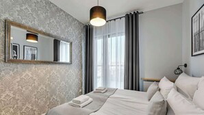 Habitación de hotel con una cama grande, un espejo, una ventana con cortinas y vistas a la ciudad.