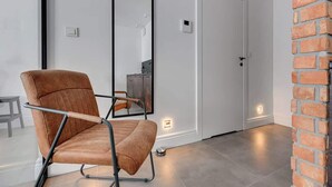 A modern room with a leather chair, a white door, and a brick wall. - Aura III 36 Deluxe | River View | City Center (Gdańsk)