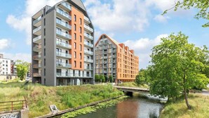 A modern apartment building with balconies, a river, and a bridge. - Aura III 36 Deluxe | River View | City Center (Gdańsk)