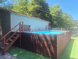 Una piscina con muelle de madera y escaleras que conducen a una zona techada.