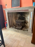 Una chimenea tradicional con un horno de metal, un extintor y un piso de baldosas.