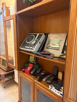 Un mueble de madera con radios antiguas, un cuadro enmarco y una colección de teléfonos móviles antiguos.