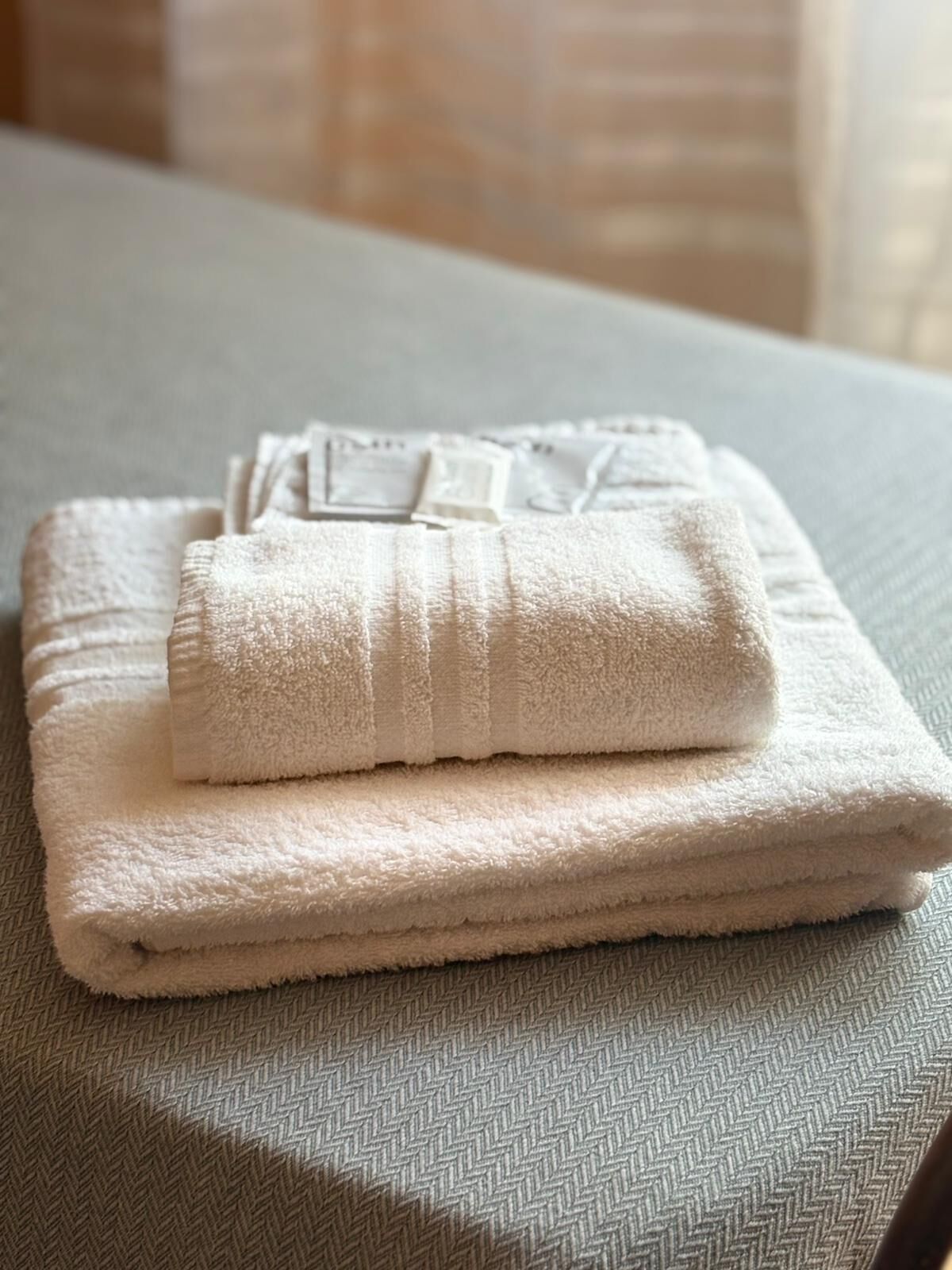 A neatly folded white towel on a textured bedspread.