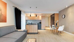 Un salon moderne avec un canapé, une table basse en verre et un coin repas comprenant une table et des chaises.