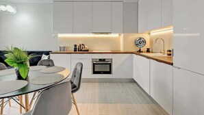 Uma cozinha moderna com armários brancos, bancada de madeira e forno embutido.