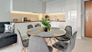 Uma área de refeições moderna com uma mesa redonda, cadeiras estofadas cinzentas e um vaso de planta.