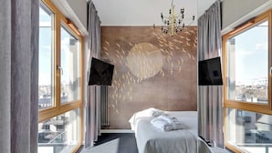 Une chambre d’hôtel moderne avec un grand lit, une télévision et une vue sur la ville.