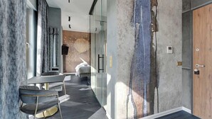 Une chambre d’hôtel moderne avec une paroi en verre, une table ronde et un lit.