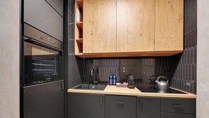 Una cocina moderna con horno empotrado, un mueble superior de madera y encimera negra.