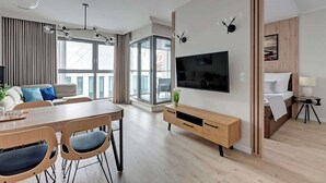 En moderne stue med spiseplads, stort tv og en væg med trædetaljer.