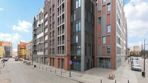 Een modern gebouw met een glazen gevel, een duidelijke ingang en een heldere lucht.