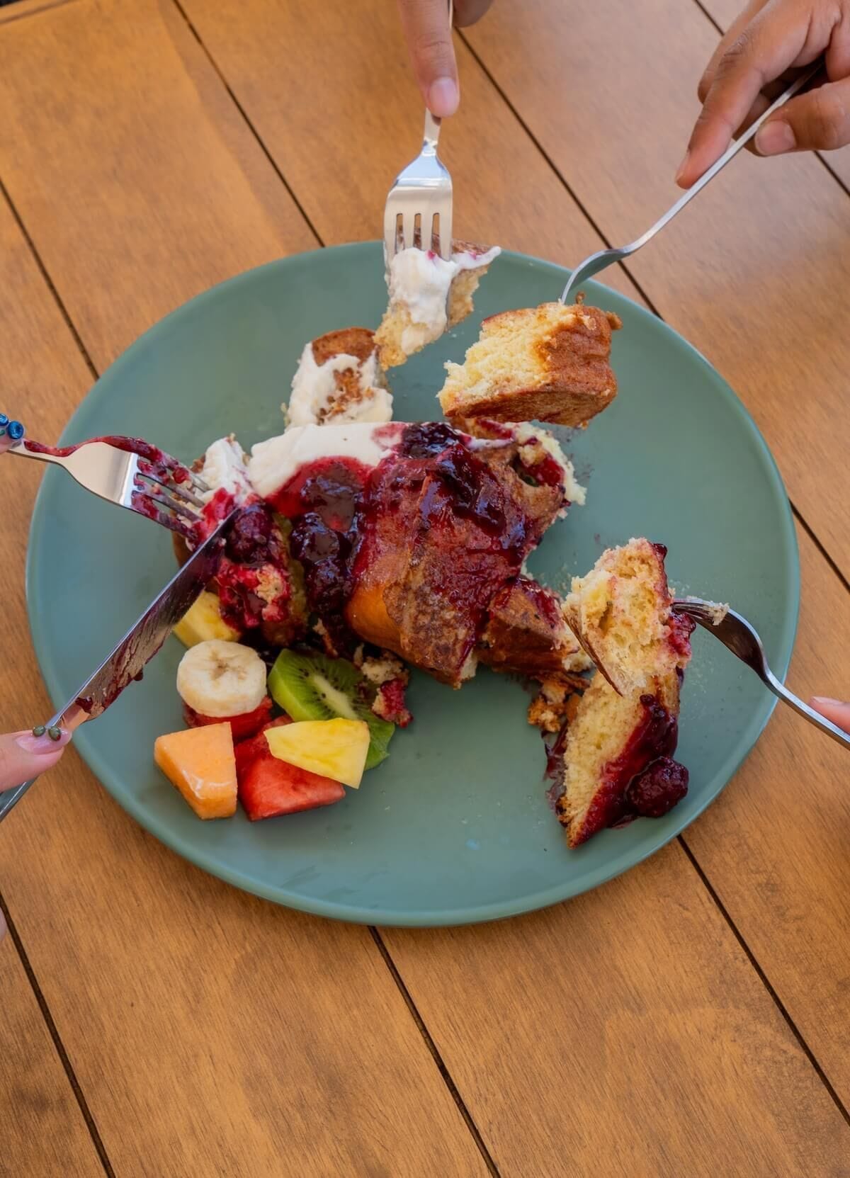 A plate with a dessert consisting of cake, ice cream, and fruit pieces.