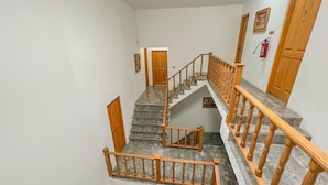 Una escalera de varios niveles con barandillas de madera y un extintor en la pared.