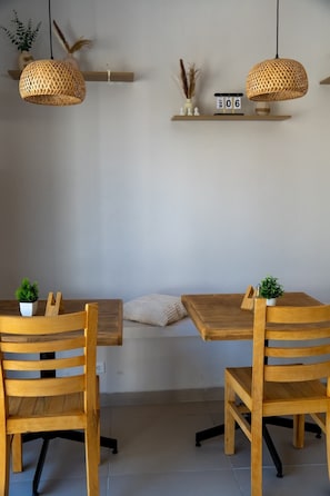 A dining area with a wooden table and chairs, two hanging rattan lamps, and a wall-mounted shelf with decorative items. - Amet Boutique Hotel (La Paz)