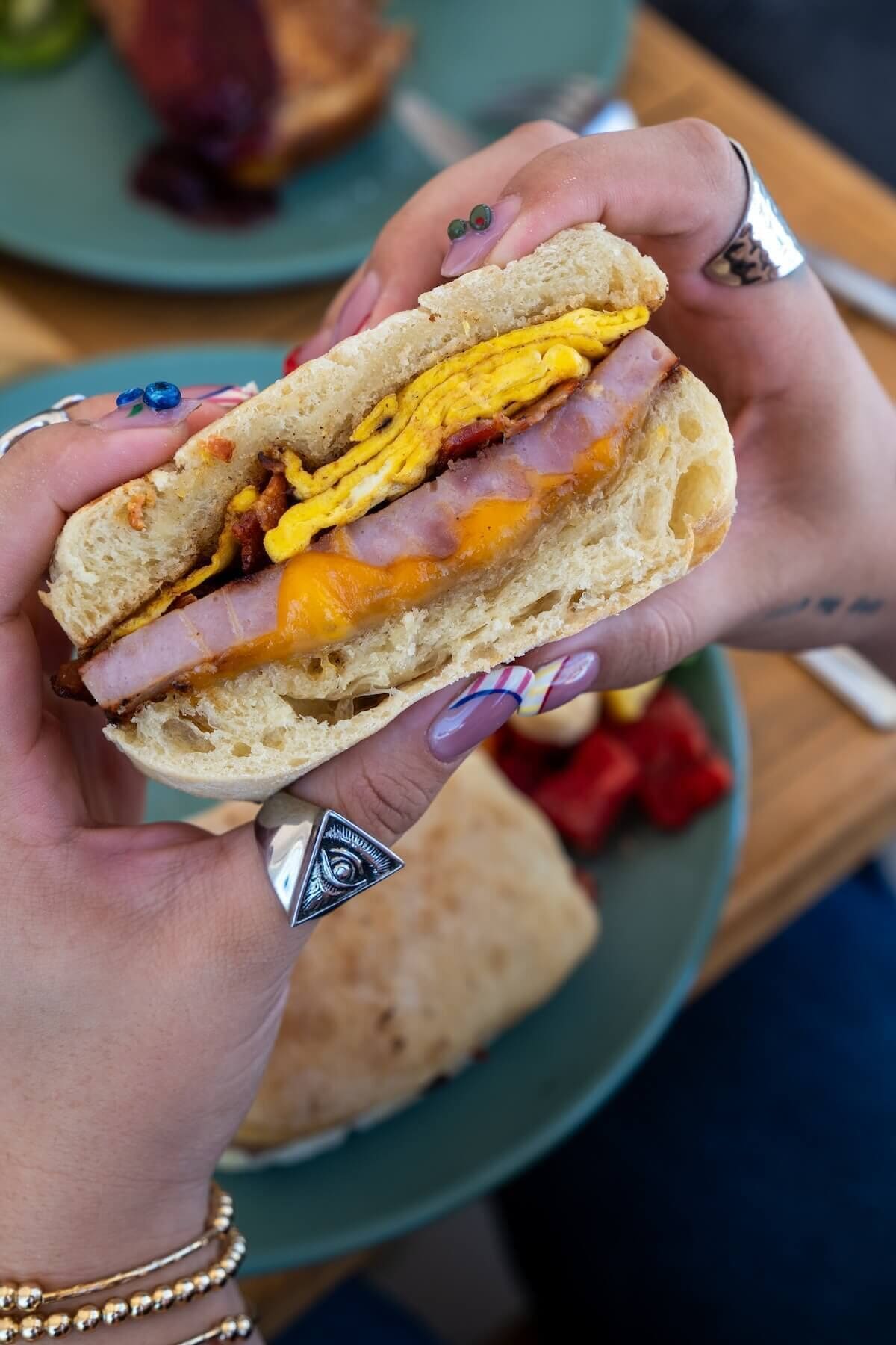 A sandwich with visible layers of egg, ham, and cheese.