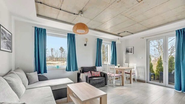 A modern living room with a sofa, a coffee table, and a dining area with chairs and a table.