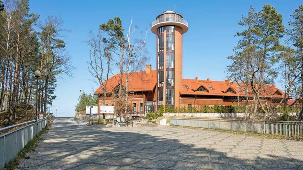 Un bâtiment doté d’une tour, d’une allée pavée et d’arbres.