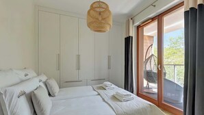 A bedroom with a bed, white wardrobe, and a balcony with a chair. - Gdynia Orłowo | 450 metres to the Beach (Gdynia)
