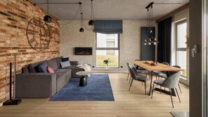 Een moderne woonruimte met een bakstenen muur, een bank, een eettafel en een groot raam.