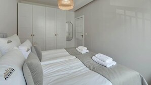 A hotel room with a bed, a wardrobe, a mirror, and a hanging light fixture. - Szafarnia 9B | Next to Marina | 2 Parking spots (Gdańsk)