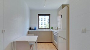 A compact kitchen with a window, a white table, and a refrigerator. - Szafarnia 9B | Next to Marina | 2 Parking spots (Gdańsk)