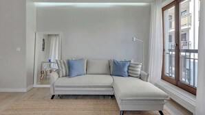 A modern living room with a sectional sofa, a large window, and a view of the outside. - Szafarnia 9B | Next to Marina | 2 Parking spots (Gdańsk)