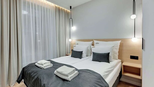 Une chambre d’hôtel moderne avec un grand lit, des tables de chevet et un rideau.