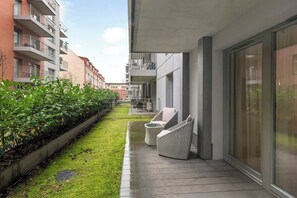 A modern apartment with a balcony, a small garden, and a seating area with two chairs. - Grano Residence 2 | Riverside | Parking (Gdańsk)
