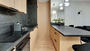 Une cuisine moderne avec des plans de travail en marbre noir, des meubles en bois et un îlot central doté d’un plan de travail noir.