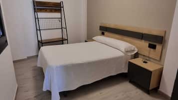 A bedroom with a bed, a nightstand, a wooden ladder, and a ceiling light.
