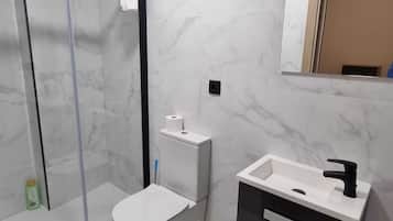 A modern bathroom with a glass shower enclosure, a toilet, and a vanity with a sink and mirror.