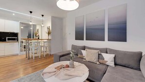 A modern living room with a grey sofa, a coffee table, and artwork on the wall. - Aura 196A | River View | City Centre & Parking (Gdańsk)