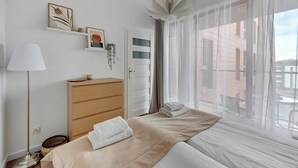 A hotel room with a bed, a dresser, a lamp, and a window with a view. - Aura 196A | River View | City Centre & Parking (Gdańsk)