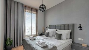 A modern bedroom with a large bed, grey curtains, a potted plant, and a geometric pendant light. - Brabank 17 | Riverside & Balcony | Parking (Gdańsk)