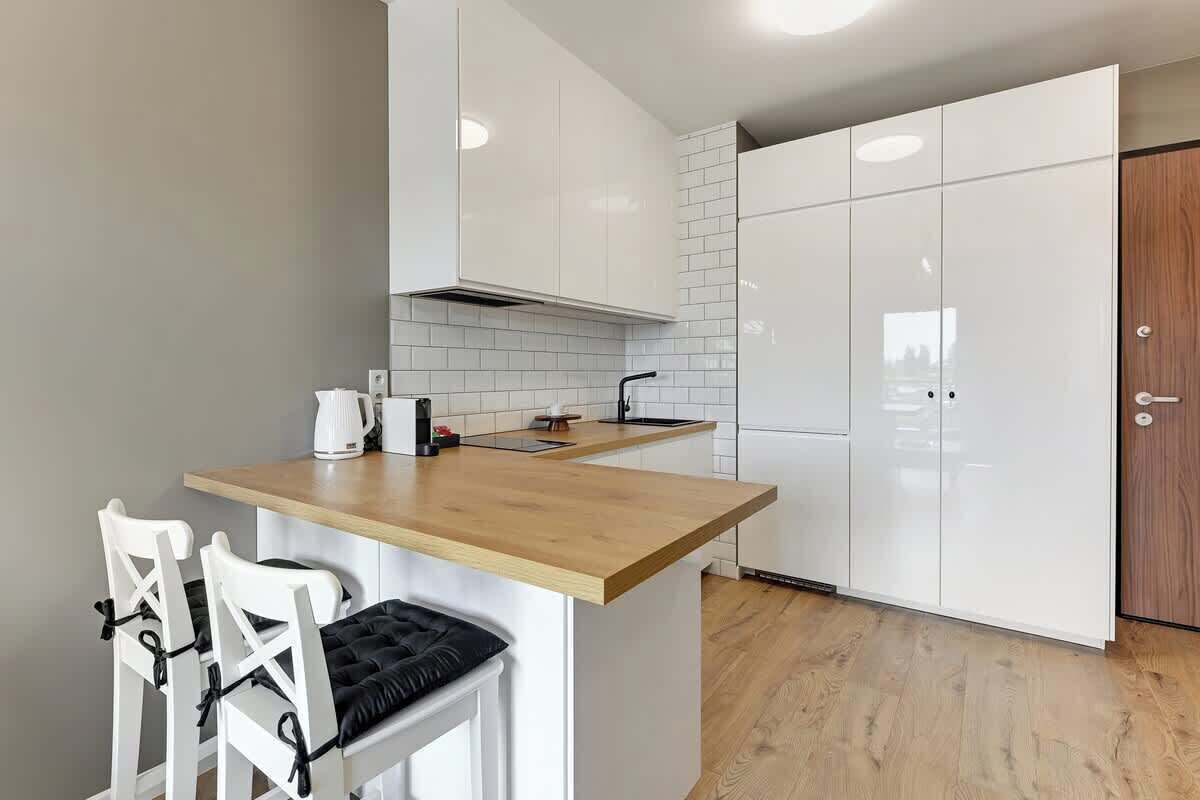 A modern kitchen with white cabinets, a wooden countertop, and a built-in stove.