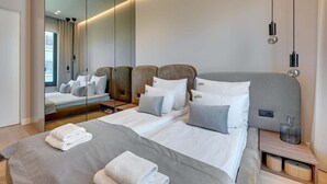 A modern hotel room with a large bed, a bedside table, a mirror, and a view of the room's interior. - Brabank 26 | Riverside & Balcony | Parking (Gdańsk)