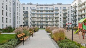 A multi-story residential building with balconies, a central pathway, and a playground. - Angielska Grobla 82B | Near Old Town & Marina (Gdańsk)