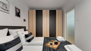 Una habitación de hotel con cama, una bandeja con artículos de cortesía y un armario.