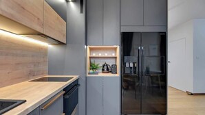Een moderne keuken met een ingebouwde oven, een koelkast en een houten aanrecht.
