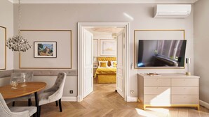 Una sala de estar moderna con comedor, televisor y cama con ropa de cama amarilla.