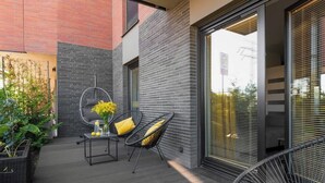 Eine moderne Außenpatio mit Tisch und Stühlen, einem Hängesessel und einer großen Schiebeglastür.