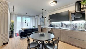 Eine moderne Küche mit Essbereich, einem schwarzen Sofa und Blick auf die Stadt.
